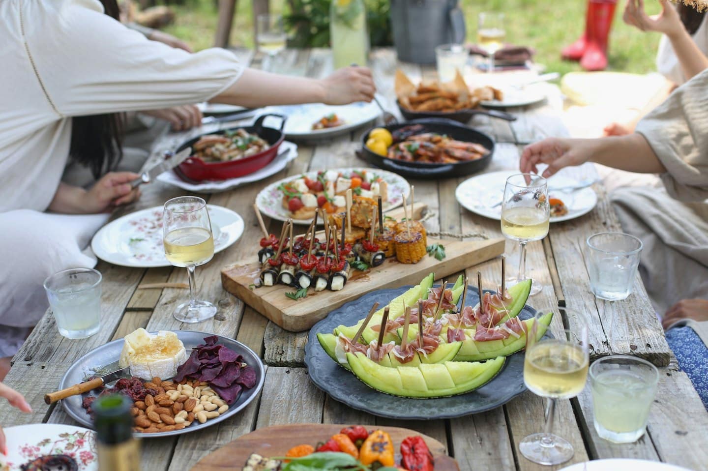 Freunde teilen eine Mahlzeit im Freien an einem rustikalen Holztisch.